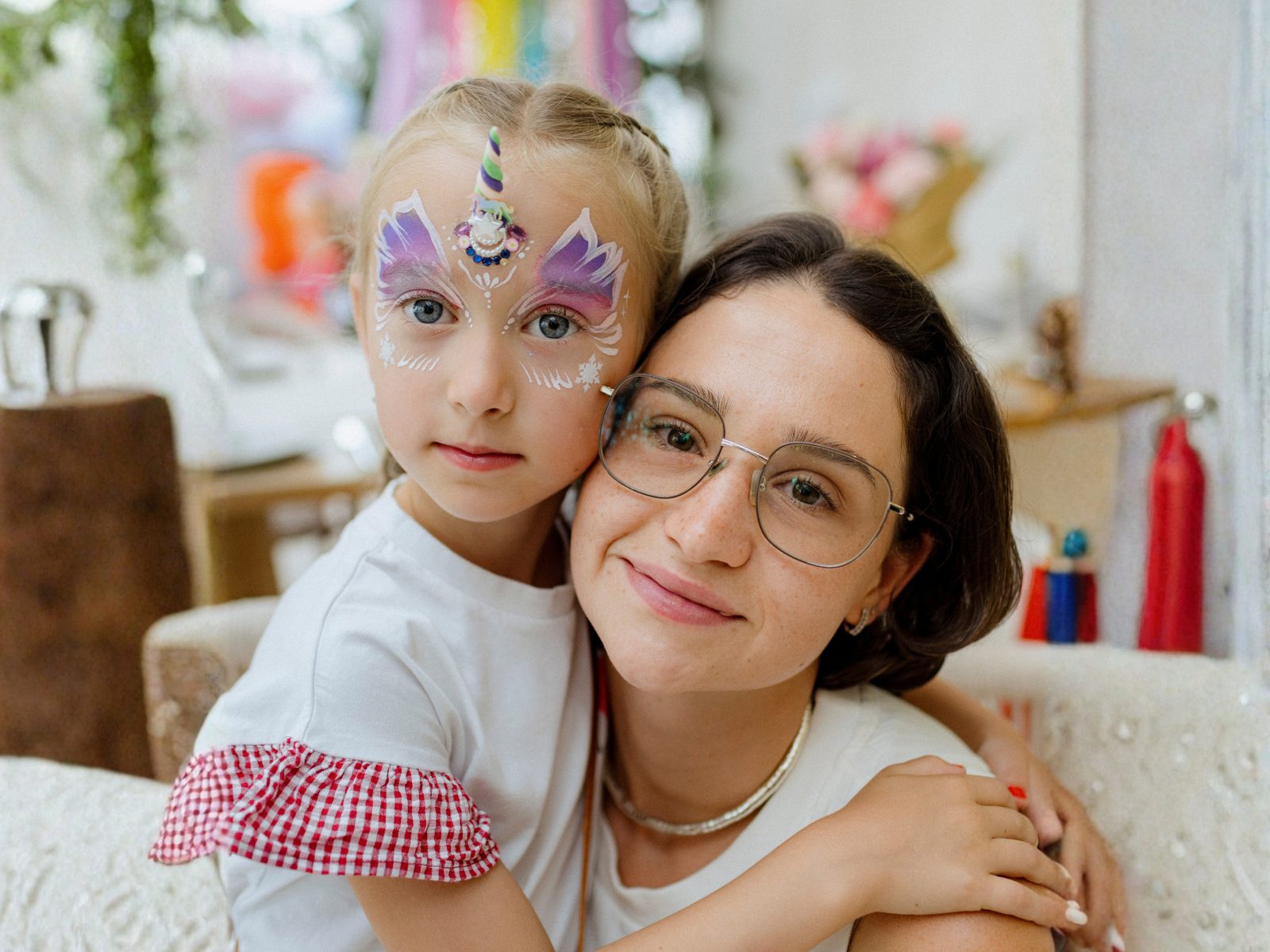 Child with unicorn face paint and a parent