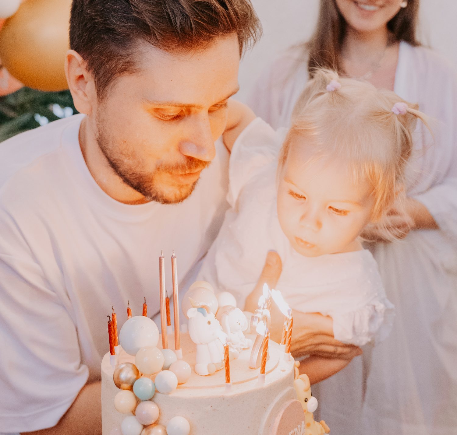 A family lighting the candles on a Tiny birthday cake