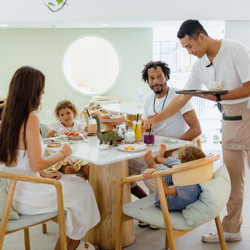 Family at a table with drinks, food, and a server at Tiny